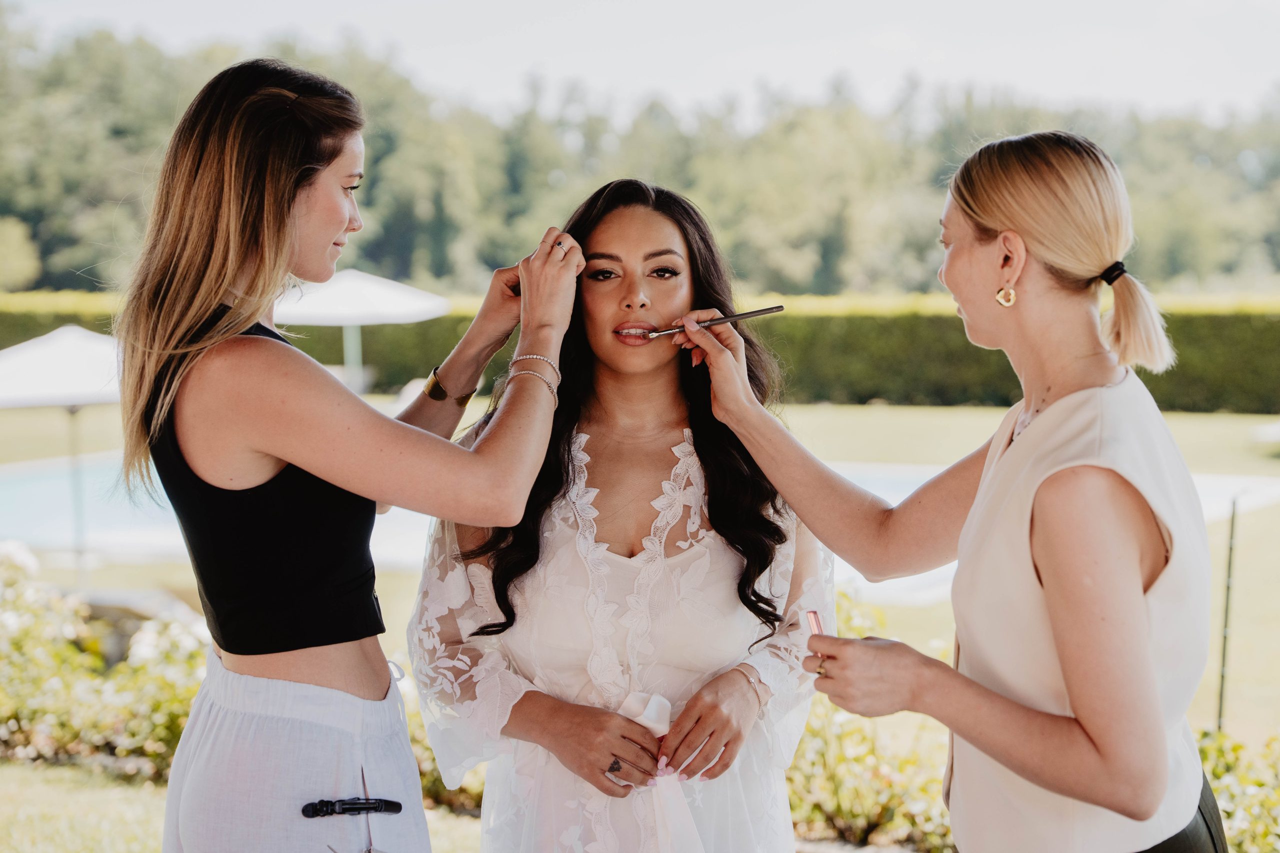 Sposa truccata da due professioniste contemporaneamente, applicazione rossetto e ritocco sopracciglia all'aperto