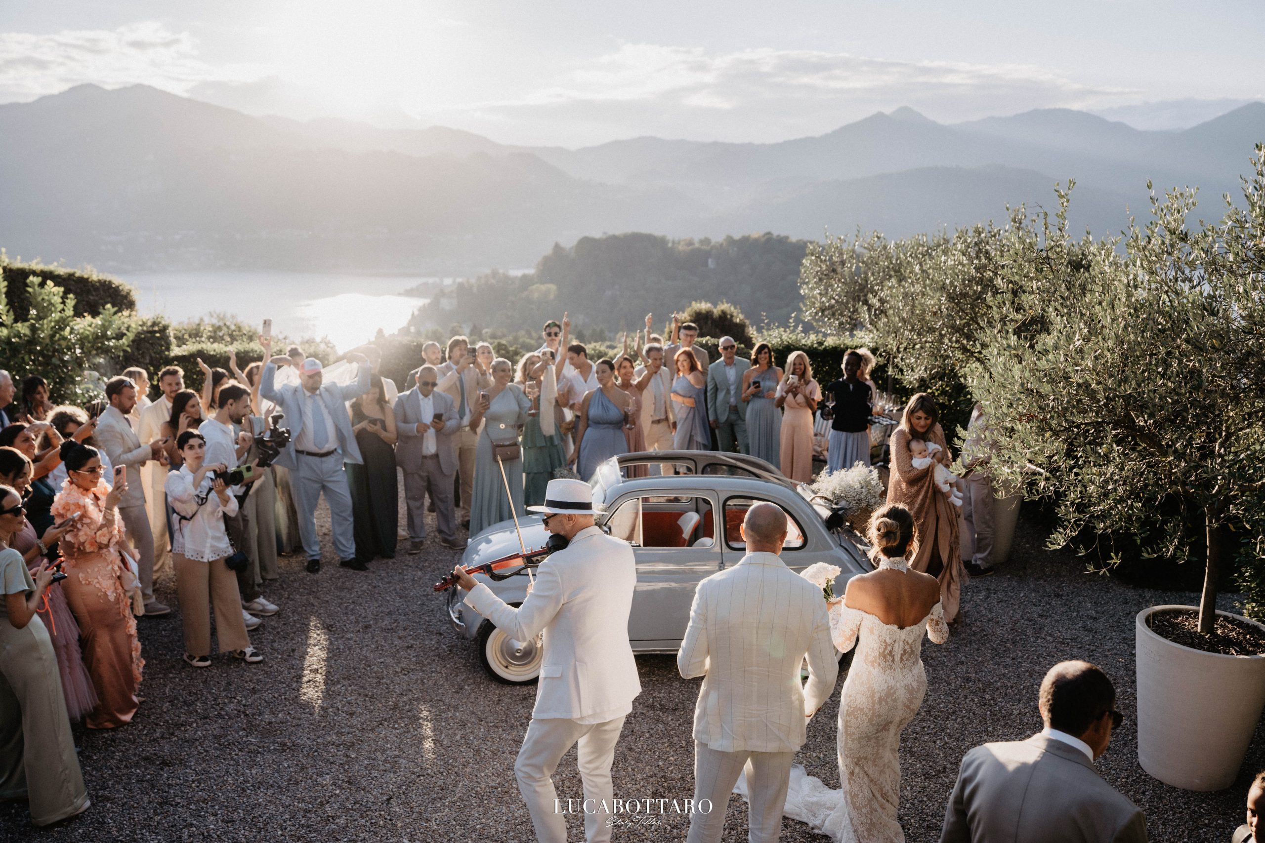 Sposi di spalle ammirano il Lago d'Orta al tramonto da La Darbia, Ameno — location matrimoni Lago d'Orta